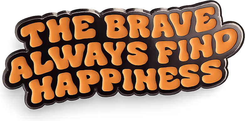 The enamel pin: THE BRAVE ALWAYS FIND HAPPINESS in gold lettering on black.